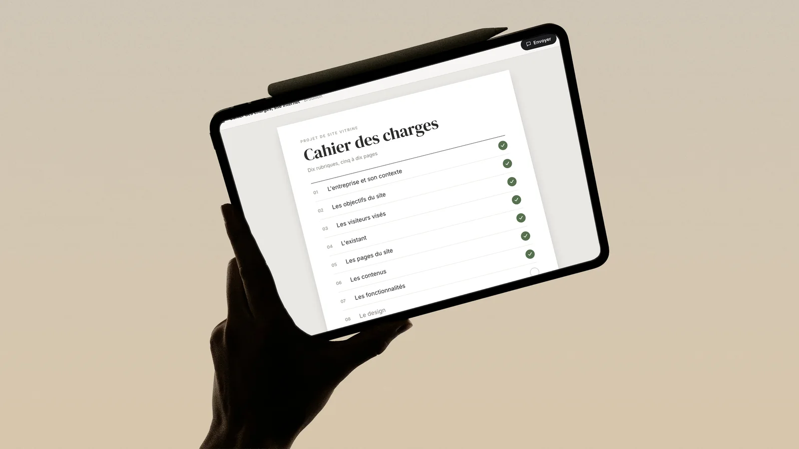 Cahier des charges d'un site internet ouvert sur une tablette tenue en main, avec ses rubriques cochées une à une